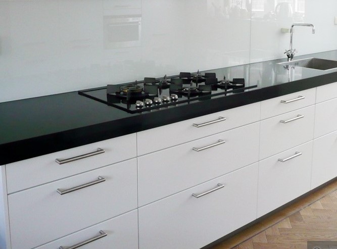 Een glazen keuken achterwand aan een wand gemonteerd