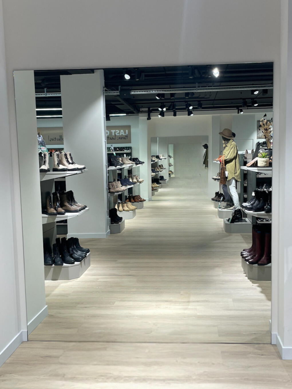 Paskamerspiegel groot formaat in een standaard verzilverde kleur. Hangend aan de muur in een schoenenwinkel.