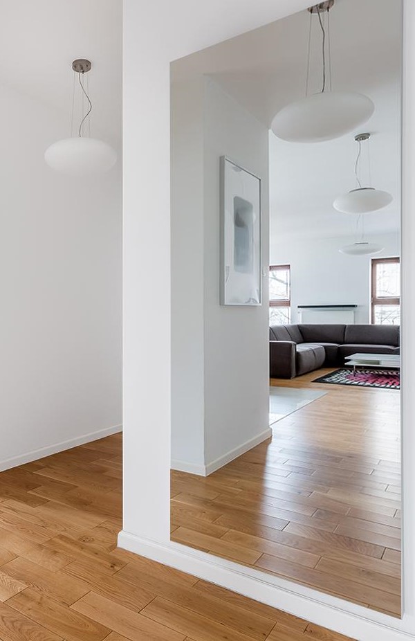 Brede verzilverde spiegel op maat hangend aan de muur