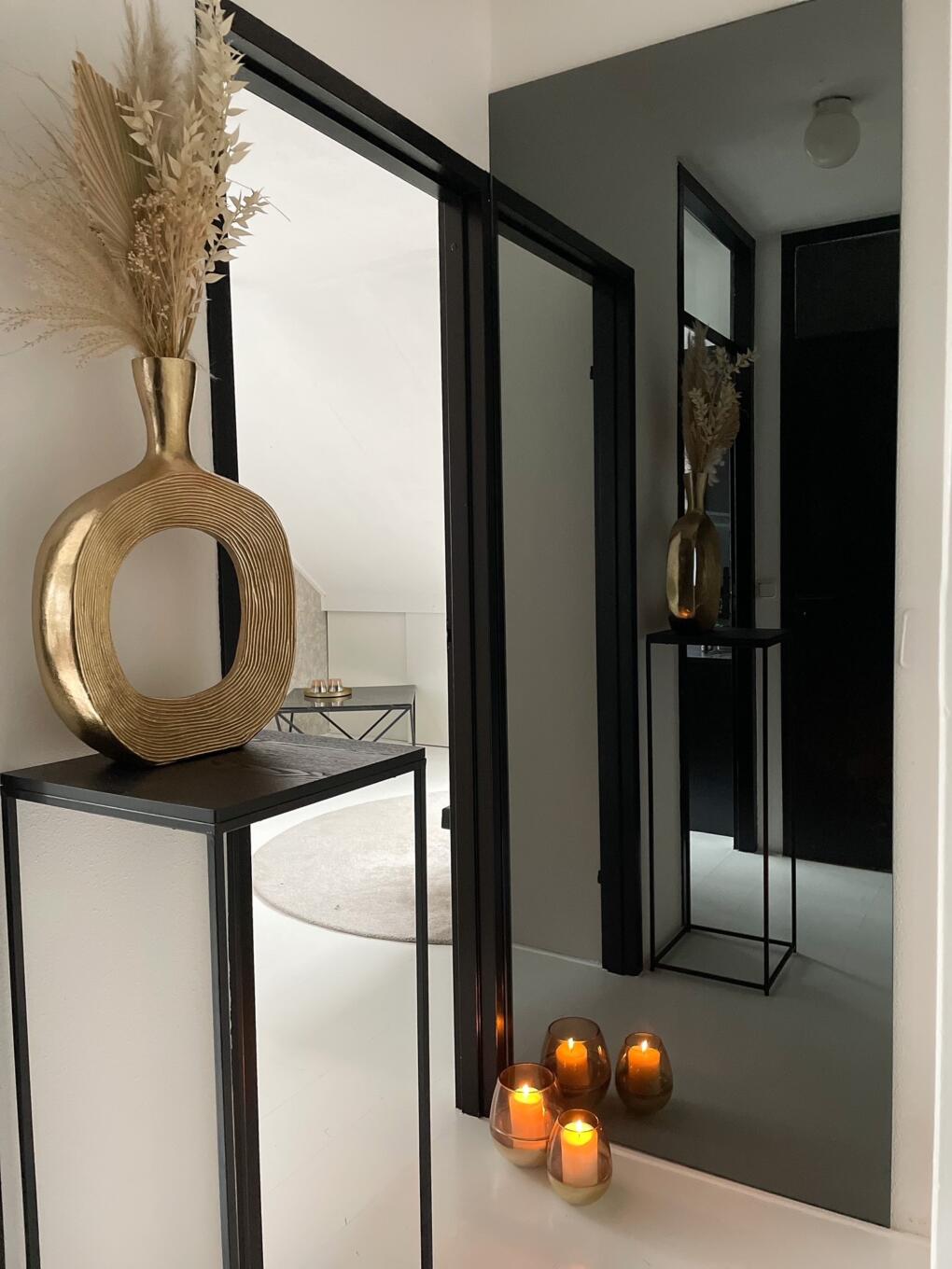 Smalle spiegel in verzilverd grijs hangend aan de muur op de overloop.